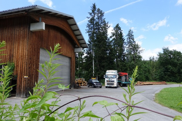 Entrindungsmaschine mit Begleitfahrzeug vor Firmenhalle